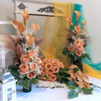 Zestaw nagrobny w Cieniu Kasztanowca nr 380 Zestaw nagrobny w Cieniu Kasztanowca nr 380 to unikatowa i piękna kompozycja kwiatowa. Zestaw składa się z kompozycji leżącej oraz bukietu.  Kompozycja jest przede wszystkim jest niezwykle elegancka i duża. Składają się na nią kolejno : róże i gumowe kalie .10 kalii w kolorze cappuccino o długości 72 cm  zostało ułożone warstwowo w kuli kwiatowej. Całość osadzona jest na betonowej podstawce, by zabezpieczyć kompozycję przed wiatrem. Kalie i róże pięknie ze sobą współgrają tworząc harmonijną całość. Bukiety stworzone do zestawu będą strzeliste , w kolorze naturalna biel, z pięknymi powyginanymi kaliami. Możliwość zamówienia w następującej kolorystyce: czerwony, biały, fioletowy, bordo, różowo-kremowy, szary, szaro-różowy, szaro-fioletowy, szaro-niebieski. Wiązanka będzie prezentować się elegancko na praktycznie każdym większym nagrobku. Wszystkie kwiaty wykorzystane w kompozycji to wysokiej jakości sztuczne kwiaty. Jeżeli spodobała się Wam nasza Kompozycja nagrobna Zestaw nagrobny w Cieniu Kasztanowca nr 380,  możemy również przygotować dla Państwa zestaw w tej kolorystyce, z innymi elementami dekoracyjnymi, na przykład z bukietem do wazonu, stroikiem czy wiankiem. Wystarczy napisać do nas wiadomośc prywatną, by ustalić szczegóły zamówienia Wymiary Zestawu nagrobnego w Cieniu Kasztanowca nr 380: Długość  85-90 cm Wysokość bukietów: ok. 75-80 cm Nie ma dwóch takich samych Każda z naszych dekoracji jest wykonywana ręcznie, więc gwarantujemy, że dekoracja dostarczona Wam będzie jedyna w swoim rodzaju. Ze względu na to, że nasze kompozycje wykonywane są za każdym razem ręcznie przez florystę oraz sezonowość wykorzystywanych w kompozycjach dodatków – kompozycja przygotowana dla Państwa może delikatnie różnić się od przedstawionej na zdjęciu. Gwarantujemy natomiast jakość i estetykę wykonania Państwa zamówienia.