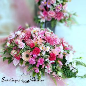 Stroik nagrobny Róż i fuksja nr 759 Stroik nagrobny Róż i fuksja nr 759 to wyjątkowa kompozycja kwiatowa.  Ta dekoracja nagrobna ma kształt łezki. Kwiaty, które wykorzystaliśmy w kompozycji uzupełniliśmy są zielonymi elementami. Klimatyczne dodatki i zielone liście tworzą wyjątkową dekorację. Kwiaty, jakie występują w tej dekoracji nagrobnej są uniwersalnej urody i dekoracja niezależnie od pory roku będzie prezentować się pięknie.  Dobrej jakości materiały oraz harmonia kompozycji pięknie zaprezentują się zarówno na ciemnym jak i jasnym nagrobku. Zielone elementy kompozycji atrakcyjnie podkreślają kolor kwiatów. Dekoracja osadzona w plastikowej, obciążonej podstawie. Śliczna delikatna kompozycja w różu tworzy niepowtarzalny klimat.